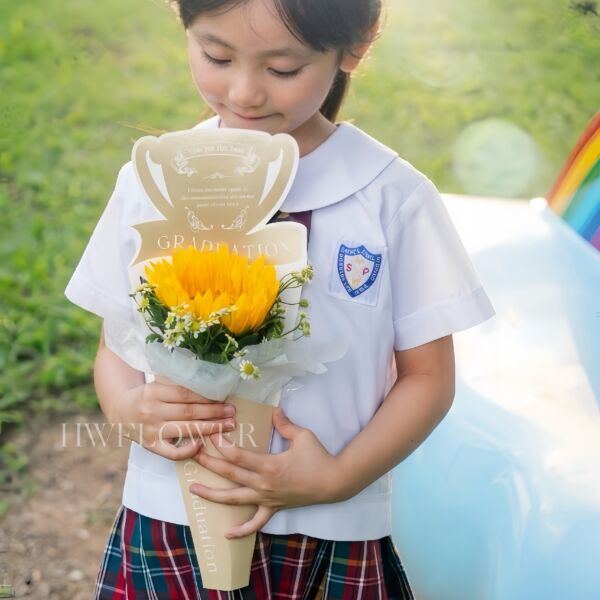 A single yellow sunflower paired with white chamomile flowers and green foliage, arranged in cream trophy-shaped wrapping.