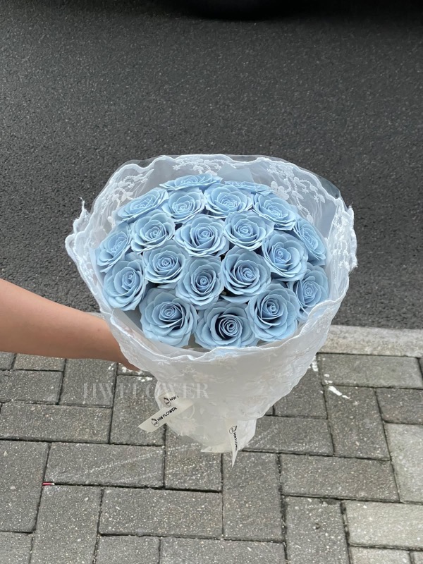 Dusty blue soap rose bouquet wrapped in delicate lace fabric, creating an elegant and romantic floral gift.